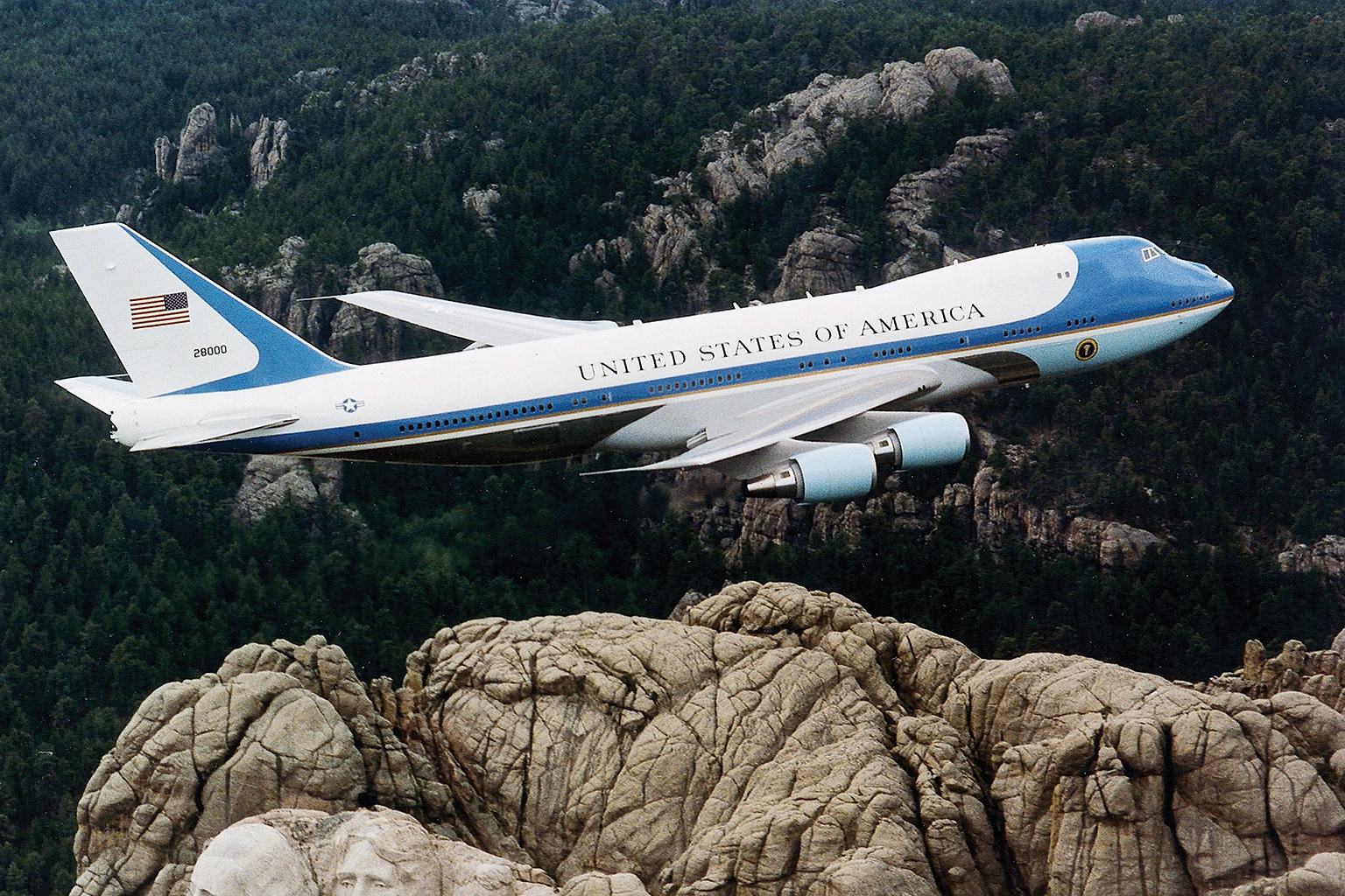 Air Force One , the typical air transport of the President of the United States of America , flying over Mount Rushmore .