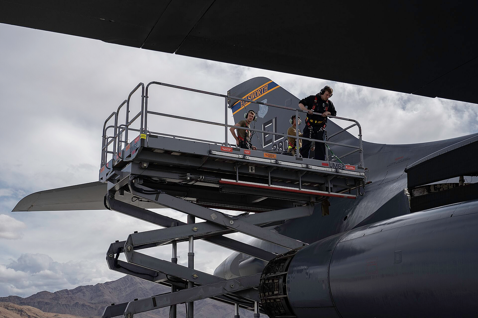 U.S. Air Force Airman 1st Class Matthew McLaughlin, aircraft hydraulics systems technician, 28th Aircraft Maintenance Squadron (AMXS), left, Staff Sgt. Alexander Moreto, aircraft hydraulics systems technician, 28th AMXS, center, and Airman 1st Class David Hearn, electrical and environmental technician, 28th AMXS, left, lower a scissor lift during Red Flag 23-2 at Nellis Air Force Base, Nevada, March 15, 2023. The B-1B Lancer can rapidly deliver massive quantities of precision and non-precision weapons against any adversary, anywhere in the world, at any time. (U.S. Air Force photo by Airman 1st Class Josephine Pepin)