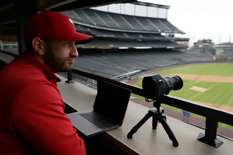 Grounded editorial scene illustrating Advance scout Justin Prinstein, known as 'The Baseball Spy,' was dismissed after recording Rockies coaching staff during a June series, raising questions about the incident.