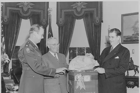 Photograph of Sen. Olin Johnston of South Carolina presenting President Truman with a turkey from Wilton E. Hall of Anderson, South Carolina, as Colonel Lewis Jackson looks on.