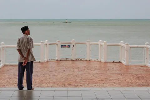 Malacca, Malaysia: A man with muslim headgear is watching the Strait of Malacca from Masjid Selat Melaka