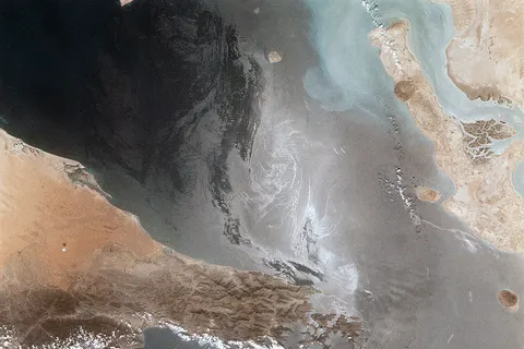 Portions of Oman, The United Arab Emirates and Iran are seen at the Strait of Hormuz (26.0N, 56.0E) in this view. A number of ship wakes can be seen in the area of the strait. Sunglint in the Persian Gulf to the northwest, accentuates the complex currents and oil slicks, seen as dark toned blue streaks on the surface. Qeshm Island, just off the coast of Iran, can be seen on the edge of the photo.