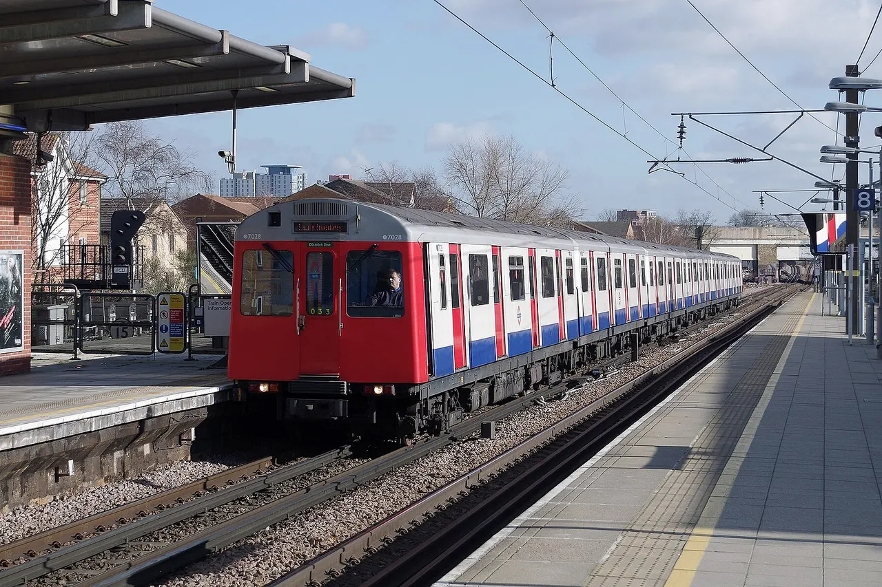 A London Underground District Line D Stock train arrives at West Ham with a westbound service.