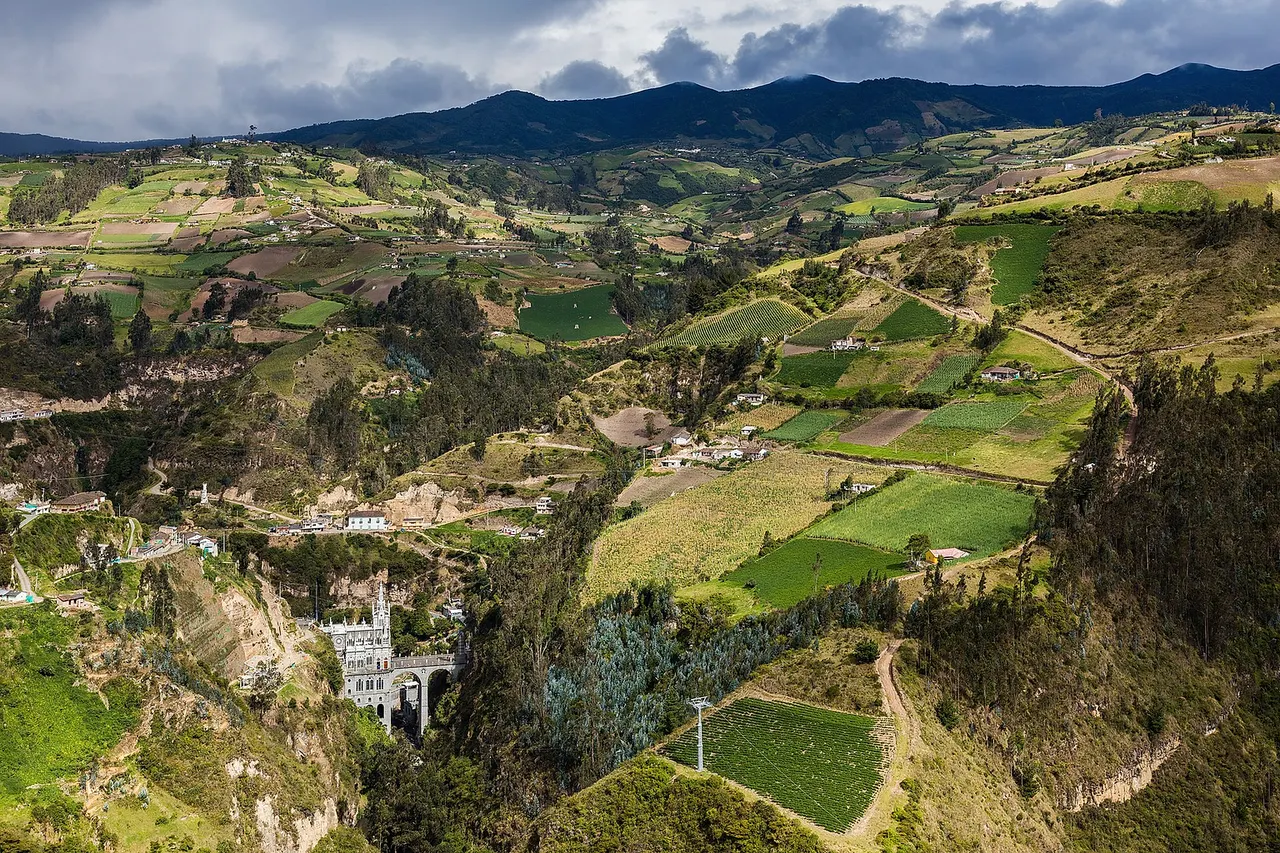 Far view of Las Lajas Sanctuary and its surroundings, a basilica church located in the southern Department of Nariño , municipality of Ipiales , Colombia. The place is a popular pilgrimage location since the apparition of the Virgin Mary in 1754. The first shrine was built by 1750 and was replaced by a bigger one in 1802 including a bridge over the canyon of the Guáitara River . The present temple, of Gothic Revival style, was built between 1916 and 1949.