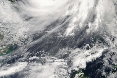 Typhoon Prapiroon formed in the western Pacific on July 31, 2006, off the coast of Luzon, the northernmost of the Philippine Islands. The tropical depression strengthened to storm status in the next day after crossing Luzon, and reached typhoon status by early August 2, as it continued east-northeast across the South China Sea towards the Asian mainland. The storm system was blamed for some six deaths in the Philippines as it crossed the island. As of August 3, it was predicted to make landfall in southern China not far from Hainan Island, packing forecasted winds around 115 kilometers per hour (73 miles per hour). Fishing boats were ordered into port, and rescue teams were being prepared for possible flooding and landslides. This photo-like image was acquired by the Moderate Resolution Imaging Spectroradiometer (MODIS) on the Aqua satellite on August 2, 2006, at 1:50 p.m. local time (05:50 UTC). Prapiroon had a very well-defined spiral shape and active thunderstorm systems (bright, puffy clouds) close to the eyewall. Prapiroon at the time the Aqua satellite passed overhead had a partially opened eye: the center of the storm still had some light cloud cover. Sustained winds in the storm system were estimated to be around 120 kilometers per hour (75 miles per hour) around the time the image was captured, according to the University of Hawaii’s Tropical Storm Information Center. The high-resolution image provided above is provided at the full MODIS spatial resolution (level of detail) of 250 meters per pixel. The MODIS Rapid Response System provides this image at additional resolutions.