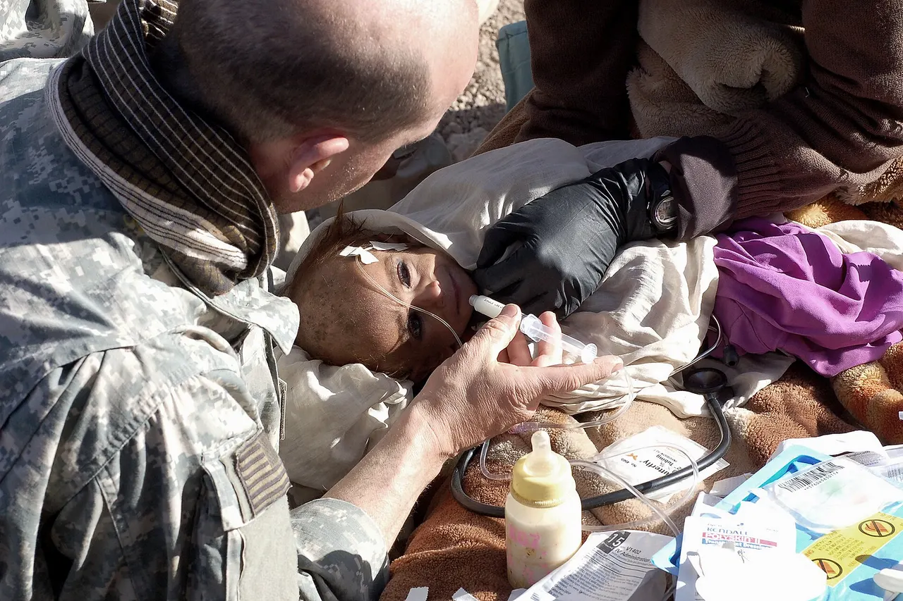 A malnourished Afghan child, weighing 14 pounds (6.4 kg) at 18 months of age, is treated by a US Army medical team member in Paktya, Afghanistan.