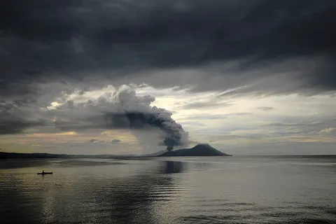 As a fisherman waits patiently for the fish to bite, Tavurvur belches ash and pumice into the twilight.