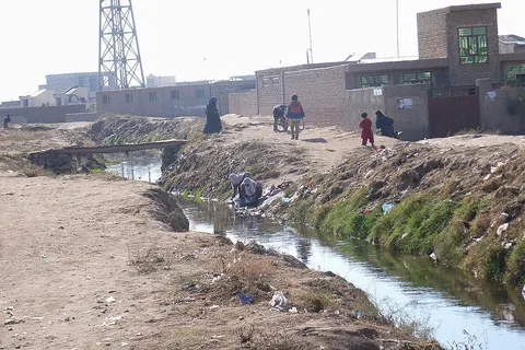 Drainage channel which also collects the greywater from the surrounding houses. A lady is washing clothes in the channel. (Photo: Nov. 2009, N. Khawaja, Herat)