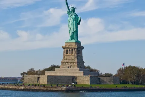 Statue of Liberty (more formally, Liberty Enlightening the World , and more colloquially, Lady Liberty ) is a structure located on Liberty Island in New York Harbor , presented to the United States on the centennial of the signing of the American Declaration of Independence as a gift from France . It was designed by Frédéric Bartholdi and gets its green coloring from patination of the outer copper covering. The statue is world-renowned for being the first thing sea-borne visitors, immigrants, and returning Americans see upon entering New York Harbor and has been known as a beacon of freedom to much of the world. It earned UNESCO World Heritage Site status in 1984.