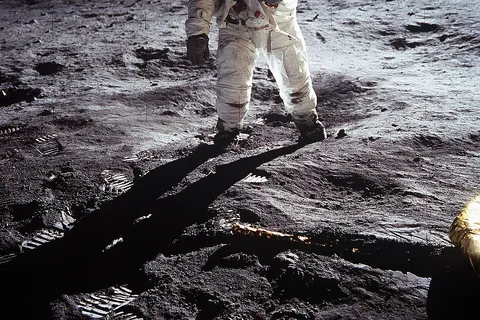 Short description : Astronaut Buzz Aldrin on the Moon Full description : Astronaut Buzz Aldrin , Lunar Module pilot, walks on the surface of the Moon near the leg of the Lunar Module (LM) "Eagle" during the Apollo 11 extravehicular activity (EVA). Astronaut Neil A. Armstrong , commander, took this photograph with a 70mm lunar surface camera. While astronauts Armstrong and Aldrin descended in the Lunar Module (LM) "Eagle" to explore the Sea of Tranquility region of the Moon, astronaut Michael Collins, command module pilot, remained with the Command and Service Modules (CSM) "Columbia" in lunar orbit. Variations : The upper black band is an addition to the original photo, carried out for "reasons of balance". See the original photo and the explanation of the edit at NASA's website . In the expanded version of the photo, it is possible to see a horizontal white line at the top left (viewer's right) of the helmet. This is the base of the antenna that was cut in the original frame of the photo.