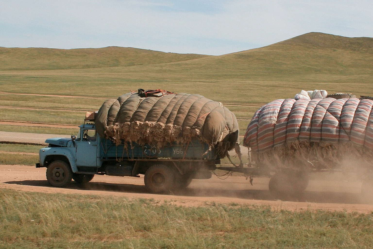 ZiL 130 with trailer transporting wool. Picture made at the main road (visible, at that time undergoing construction work) between Lün and Ulaanbaatar, Töv aimag, Mongolia. Note the many parallel tracks. The engine hood is open for better cooling.