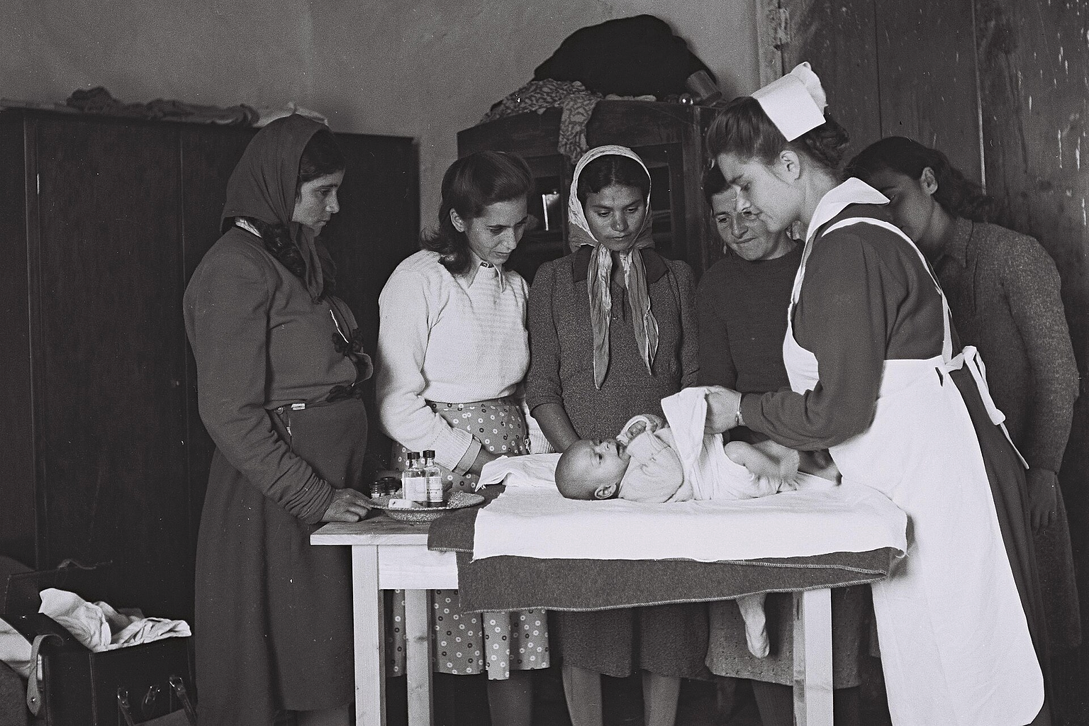 A nurse in Yehud demonstrating to young immigrant mothers how to diaper their babies (01/10/1950). אחות ביהוד מסבירה לאמהות, מהגרות צעירות , כיצד להחליף חיתול לילדיהן