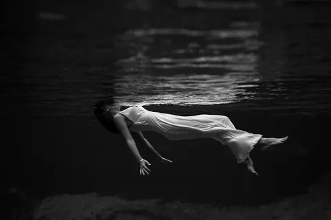 Underwater view of a woman, wearing a long gown, floating in water. Photograph by Toni Frissell at Weeki Wachee Springs , Florida , USA, 1947.