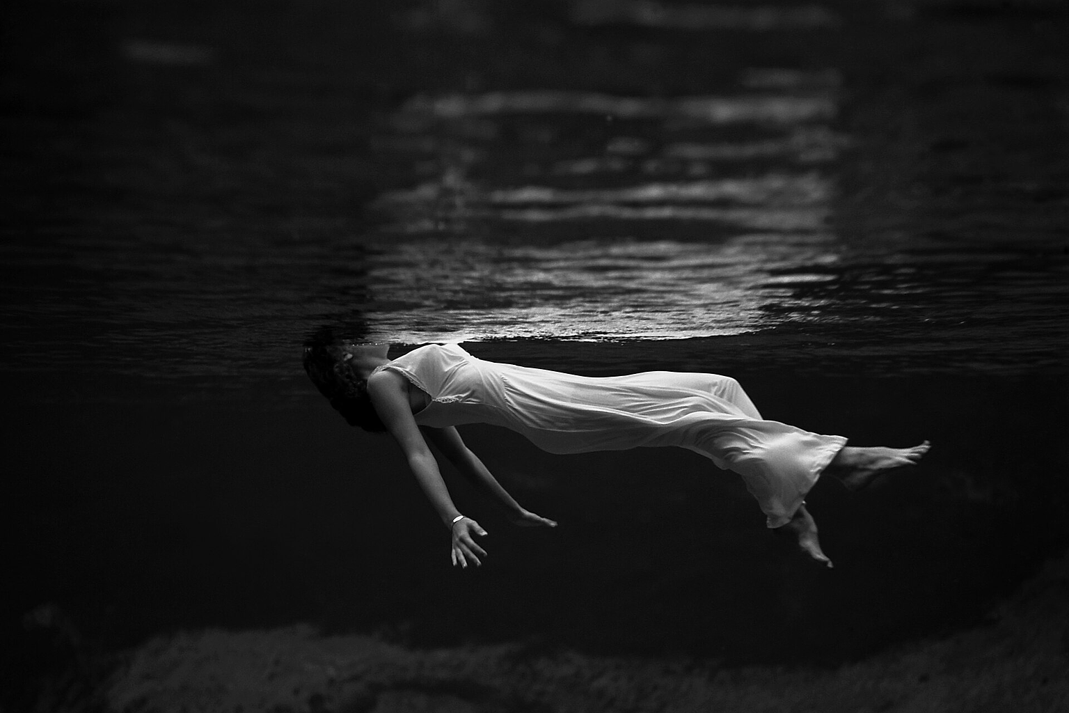 Underwater view of a woman, wearing a long gown, floating in water. Photograph by Toni Frissell at Weeki Wachee Springs , Florida , USA, 1947.