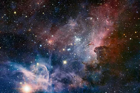 This broad panorama of the Carina Nebula, a region of massive star formation in the southern skies, was taken in infrared light using the HAWK-I camera on ESO’s Very Large Telescope. Many previously hidden features, scattered across a spectacular celestial landscape of gas, dust and young stars, have emerged. Some of these features have been annotated in Commons . Trumpler 16 (annotated) is an open cluster that contains the luminous, massive blue variable Eta Carinae, one of the brightest stars in the galaxy, possibly as much as 120 times the mass of the Sun, and emitting the light of 4,000,000 Suns. Eta Carinae is nearing the end of its life, and is surrounded by a huge nebula, cast off by numerous eruptions of the star over the last several centuries; it is expected to explode into a supernova at any time. Trumpler 14 (annotated) contains the huge double star HD 93129 A/B. The young O3 class star HD 93129 A is one of the brightest stars in the galaxy that is still on the main sequence, and with a luminosity equivalent to 3,000,000 Suns, is very nearly as bright as Eta Carinae, but this is not obvious in the photo due to obscuring nebulosities.