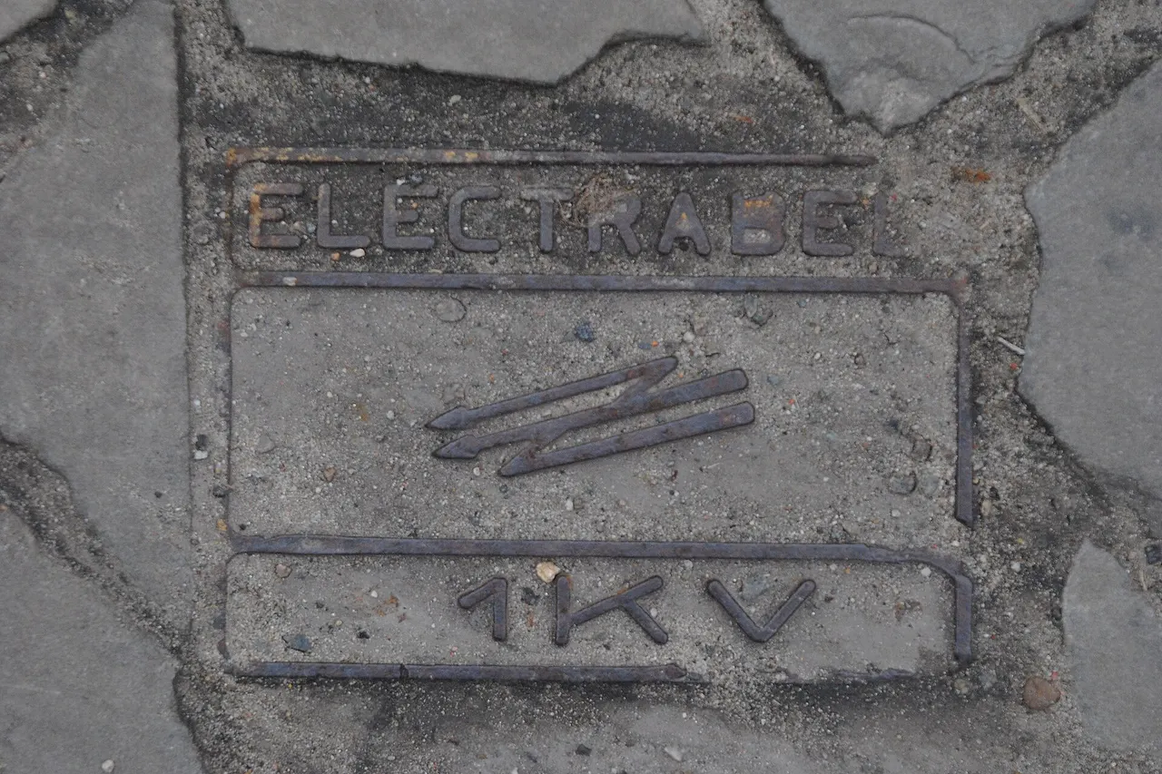 Buried cable warning plaque, lettered "ELECTRABEL 1KV", Brussels, Belgium.